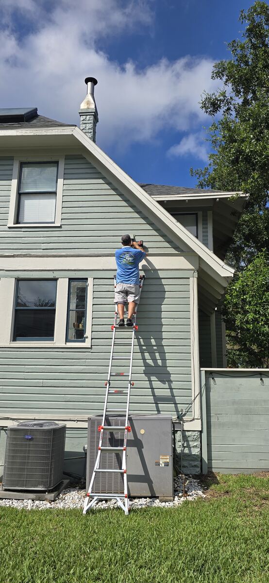 ClearFlow technician cleaning an exterior dryer vent from a ladder